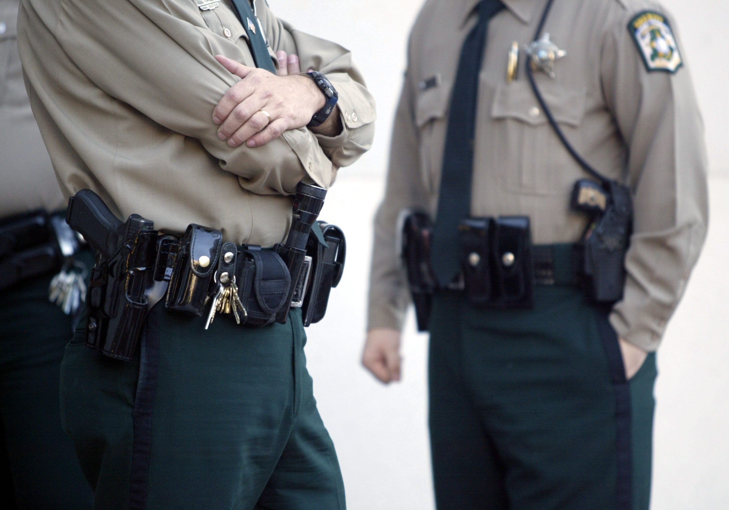 "police officers stand with handguns, stun gun and tools on their holsters."