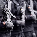 Soldier hand in black glove holding automatic machine gun during a military parade